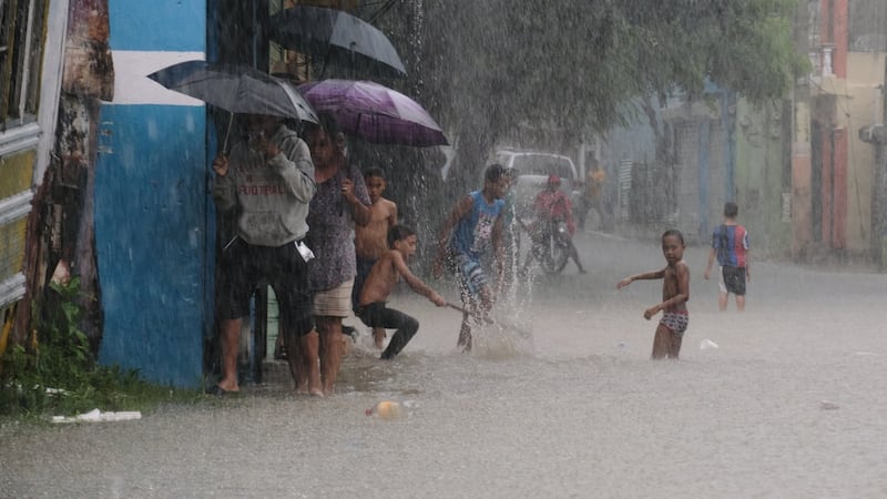Niños jugando en una calle inundada por las lluvias de la tormenta tropical Melissa en Santo...