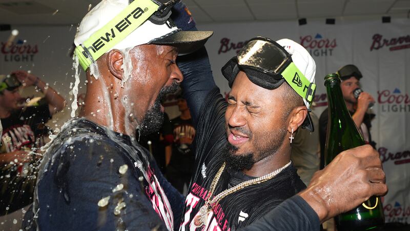 Ozzie Albies, derecha, de los Bravos de Atlanta, celebra en la casa club del equipo visitante...